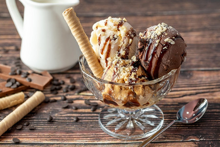 巧克力奶油和焦糖罗马人冰淇淋在玻璃碗里加了栗子和巧克力酱冷冻甜的夏天图片