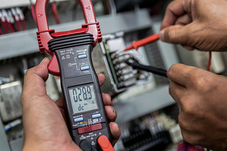 专业的部件使固定电气工程师正在用一个多米的仪表检查电气设备图片