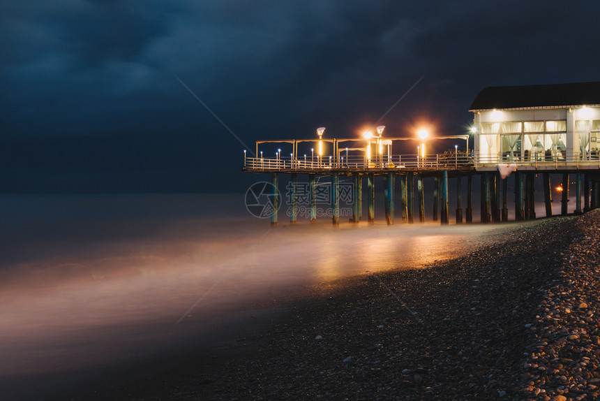 海滩暴风天气和长期露的夜晚在海上建造灯光照明设施以及反射欧洲风暴图片