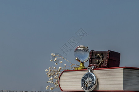 经典的象征时间旅行和学习概念背景水晶球袖手表和堆叠的书带有天空背景的图片