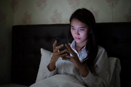 晚的上在床使用手机的亚洲妇女她笑着在家里享受快乐兴奋的夜晚图片