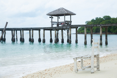 天空海岸线白木桌椅在桥后到海边的滩上游客图片