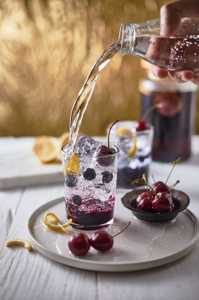 新鲜蓝莓鸡尾酒加柠檬皮和樱桃剥玻璃酒吧图片