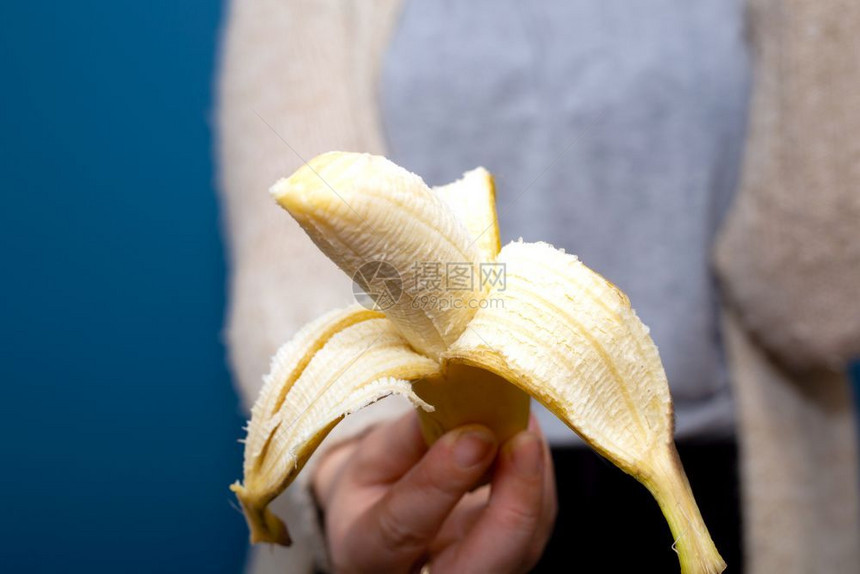 水果钾离开在蓝色背景附近手持黄色香蕉果实的人放弃健康概念特写镜头在蓝色背景附近手持黄色香蕉果实的人放弃健康概念图片