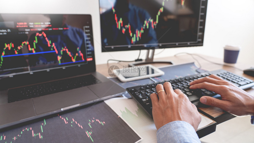 经理药片工作商人经纪或贸易商团队谈论股票市场多台计算机屏幕上的反面对交易金融图表数据分析进行投资的金融图表数据分析专业的图片