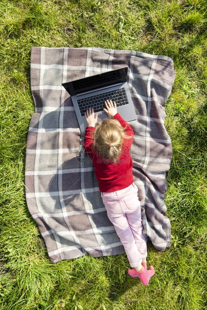 在花园里玩笔记本电脑的小女孩在线或远程教育概念顶视图或鸟瞰在花园里玩笔记本电脑的小女孩屋天线童年图片