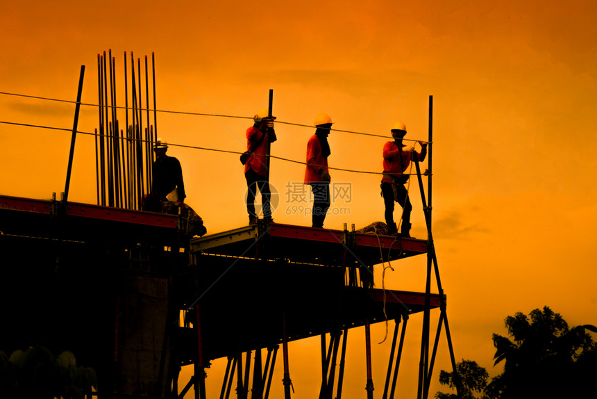公司建筑工人在一个地作施小组在重业高地面和安全概念中工作建造程人在筑地作蓝图黑色的图片
