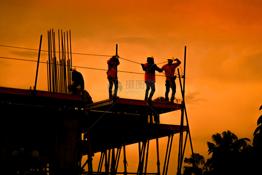 建筑工人在一个地作施小组在重业高地面和安全概念中工作建造程人在筑地作天空白色的高图片