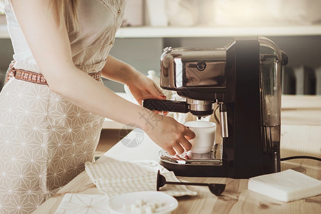 保持职员在咖啡机中制造新鲜咖啡的妇女使成为机的械磨风脚过滤器概念手图片