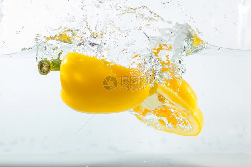 流动的生新鲜甜辣椒在水中喷洒黄色的白背景甜辣椒是一种不图片