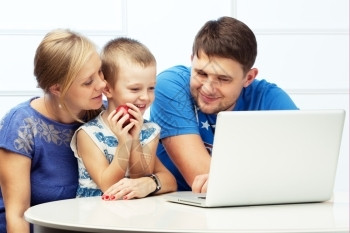 家庭煮夫孩子人们丈夫三口幸福家庭和电脑人一起坐在桌上男孩拿着苹果背景