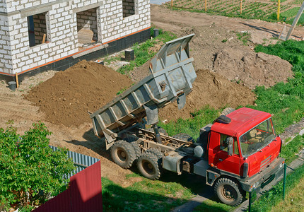 载卸车卡车和房子的是用白砖建造的自卸车把沙子带到建筑物上自卸车靠近正在建造的房子翻斗车靠近正在建造的房子卡车和是用白砖建造的自卸车将沙背景