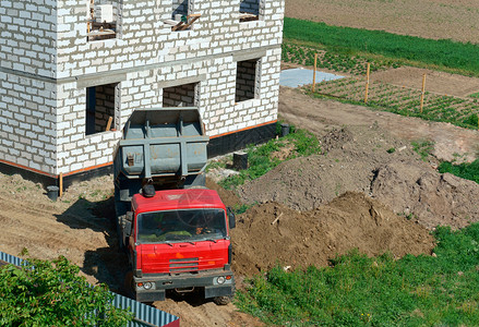 载卸车加里宁格勒结石卡车和房子的是用白砖建造的自卸车把沙子带到建筑物上自卸车靠近正在建造的房子翻斗车靠近正在建造的房子卡车和是用白砖建背景