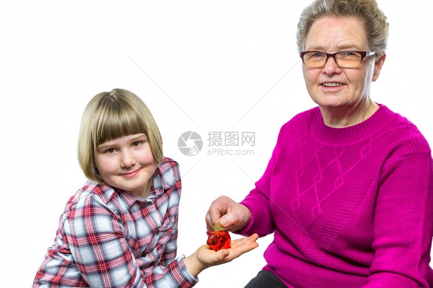 白种祖母把欧元硬币放进孙女小猪银行因为储蓄是孤立在白种背景上的为了欧洲舍内维尔图片