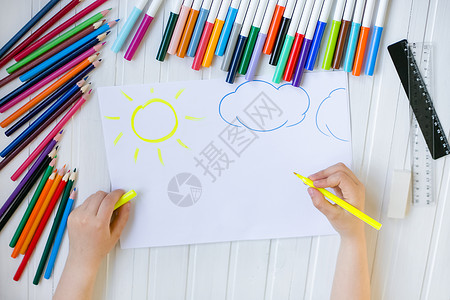 蜡笔太阳房间叶子木头童手用彩色铅笔涂在木制桌上一张白纸童子手用彩色铅笔画在纸上背景