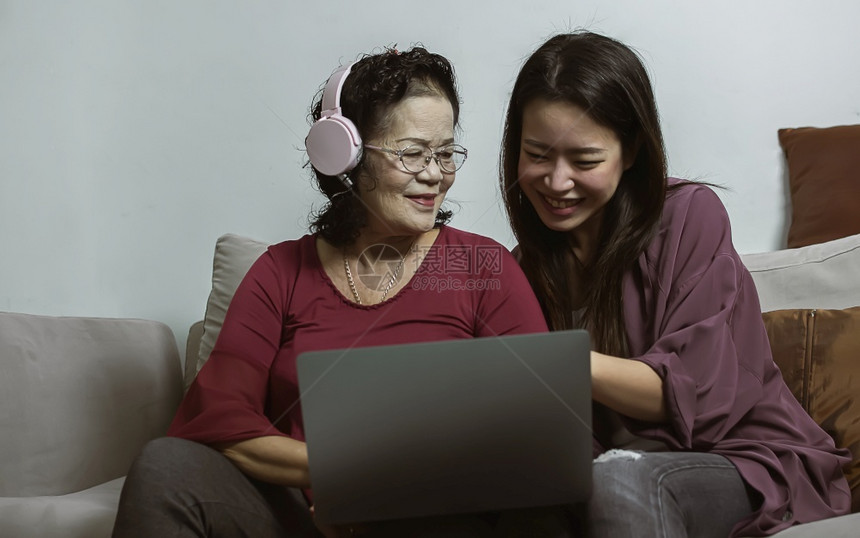 亚洲年老和轻妇女通过在家中的客厅用笔记本电脑一起在网上聊天生活方式老龄技术和新常识概念淑女放松儿图片