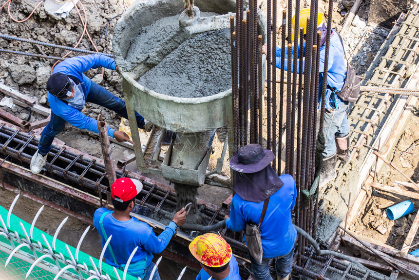 将水泥倒入地基的工人在建筑地的区进行成形工作湿的式行动图片