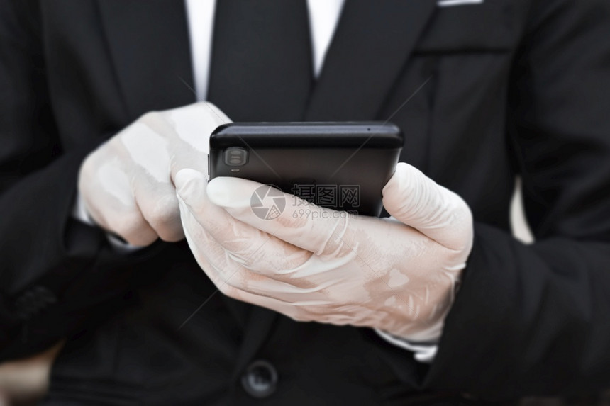 男蓝色的身戴白乳胶手套的近身商人使用智能手机进行工作时使用智能手机概念防止出现冠状或covid19的健康安全图片