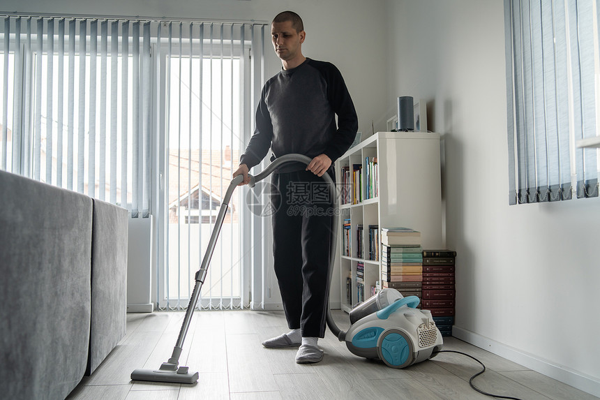 成人全长年天主教男子使用吸尘清洁器洗家里的木地板在白天做家务室卫生的男用吸尘器打扫家中的木地板干净工作图片