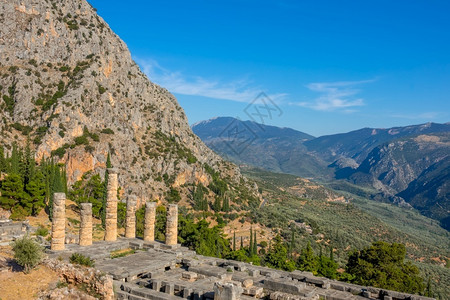 上帝柱子希腊太阳尼山脉的希腊德尔菲古废墟和绿色峡谷山希腊丘陵上的蓝天和阳光气遗产背景