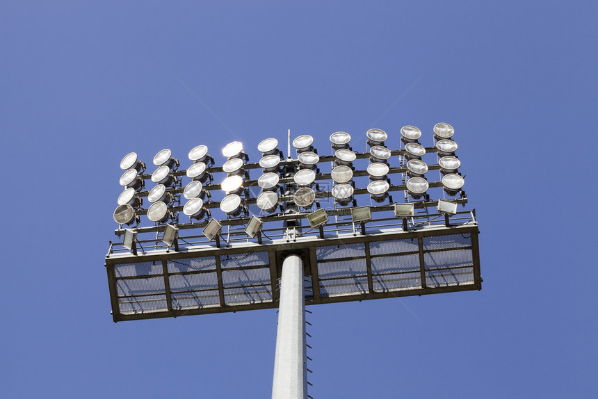 冠军在大型足球场上安装高混凝土柱子巨型探照灯一天的蓝色空有巨大探照灯发光的阴凉处图片
