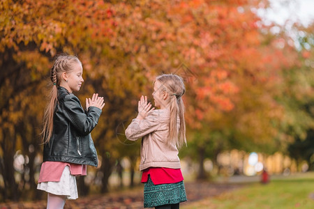 白种人秋公园的小女孩玩得开心在阳光明媚的秋天露户小可爱女孩温暖的叶子图片