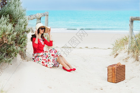 旅行夏天穿着红色的美丽女士坐在海边以回古风格休息图片