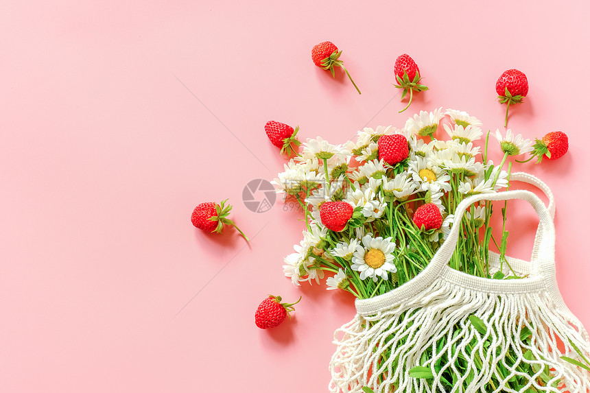 杂货平坦的红色可重复使用购物生态网袋中的一束田野雏菊和粉红色背景的草莓概念无塑料和零浪费复制空间顶视图可重复使用的购物生态网袋中图片