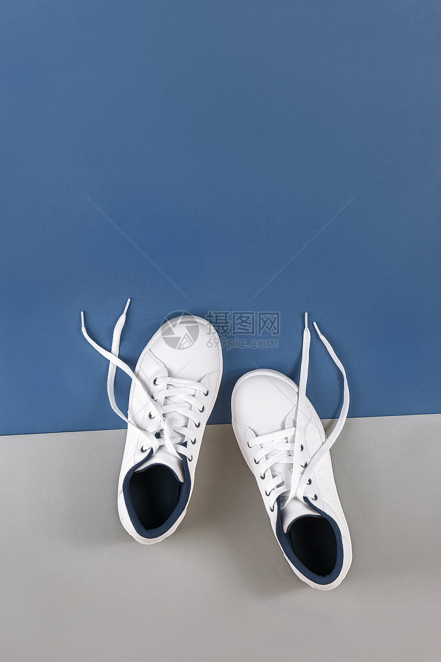 脚丫子时髦的白色运动鞋灰蓝背景上解开鞋带的运动生活方式概念顶视图平躺复制空间白色运动鞋灰蓝背景解开鞋带运动顶视图平躺复制空间赛跑图片