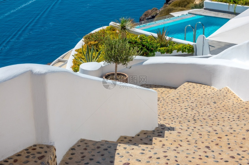 天希腊Sunny夏日在Santorini透明游泳池的度假胜地和圣托里尼太阳日CalderaStaircase和游泳池山坡上的石楼图片