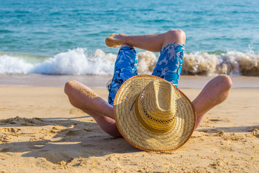 戴帽子躺在海滩上的男人图片
