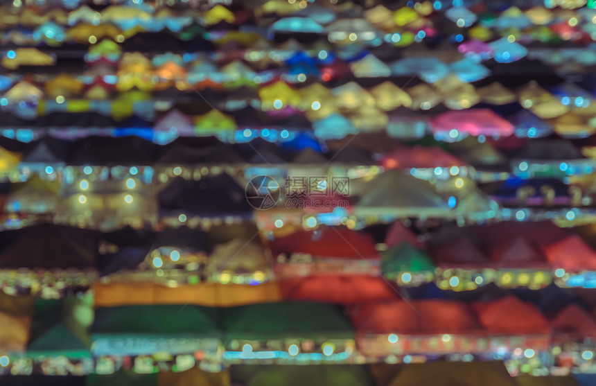 胡同散景在夜视屏蔽的音调图像中模糊的城市跳蚤场背景多彩的空中观察人们图片