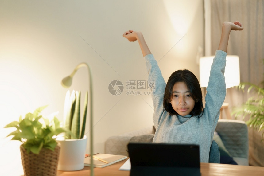社会的亚洲裔妇女在家中晚上用药片在网学习时举手增加图片