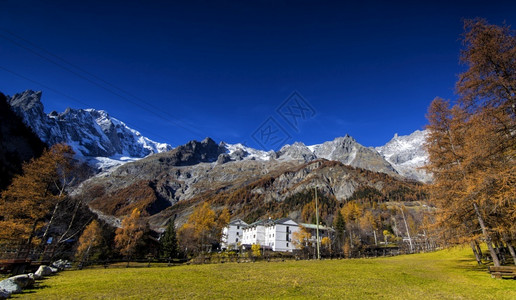 安宁运动员雄伟在阿尔卑斯山脉的一个小村庄里绿草地与巨大的山丘图片