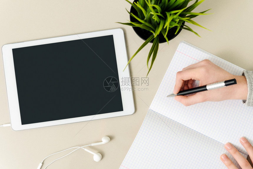写作学生工场所的概念形象女孩在一张数字平板电脑旁边的桌子上笔记本写家庭作业上面有空白屏幕耳机和花朵高天使视野多于潮人图片