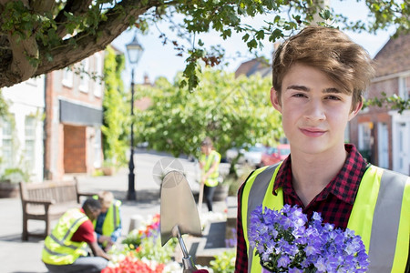 公共的人们水平帮助青少年群体种植和填充社区鲜花床位图片