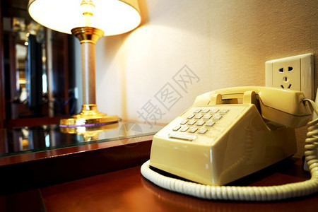 接触沟通复兴在旅馆房间墙和坡道附近的木制桌子上旧电话图片