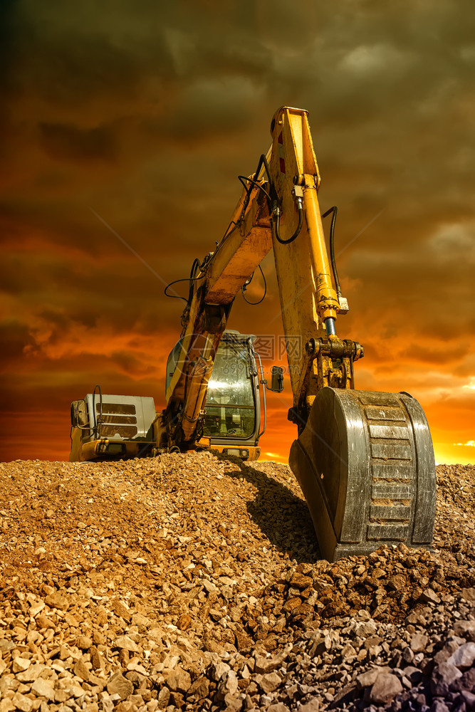 破坏惊人的日落时在建筑工地进行挖土程期间对爬行挖掘机土的透视感人图片