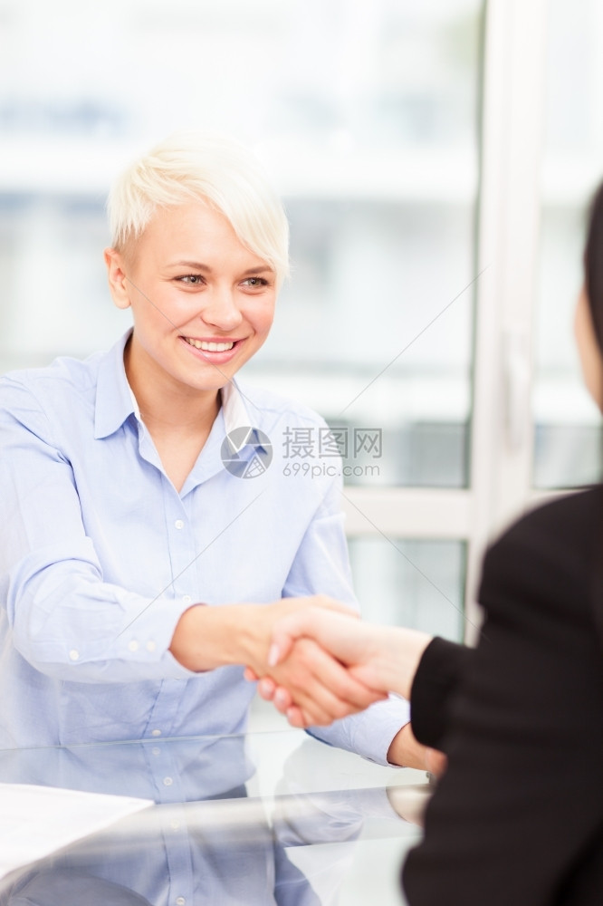 购买桌子交易办公室的女实业家之间握手图片