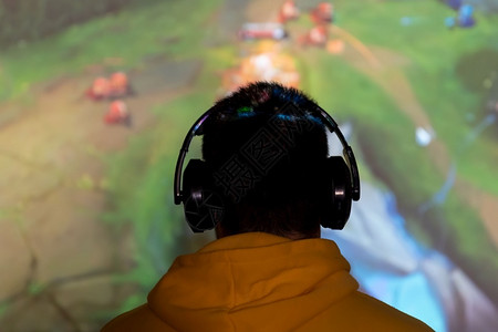 赌徒穿着耳机在屏幕前玩耍竞技场锦标赛战斗图片