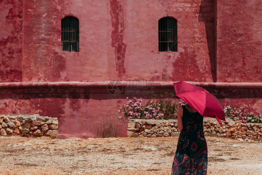 优雅的年轻寂寞姑娘拿着红色雨伞保护自己免受太阳的照射就在红古城堡旁边热的美丽图片