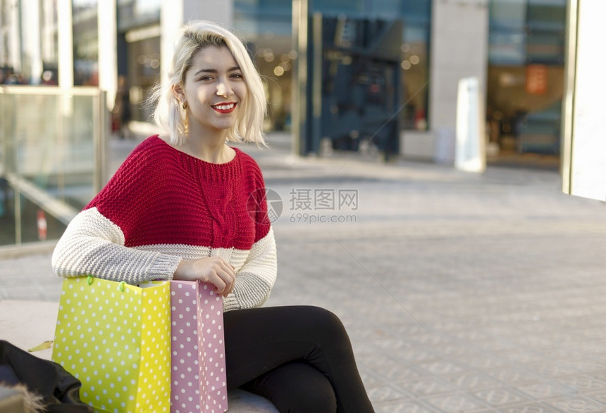 城市的女士坐在街头长椅上的一微笑沙巴坐在街头长凳上着疲惫而笑容的沙巴购物者图片