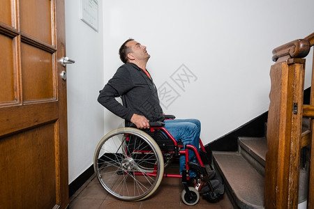 无法进入坐在轮椅上的残疾男子正面临楼梯障碍看起来好像惊慌和失望支持图片