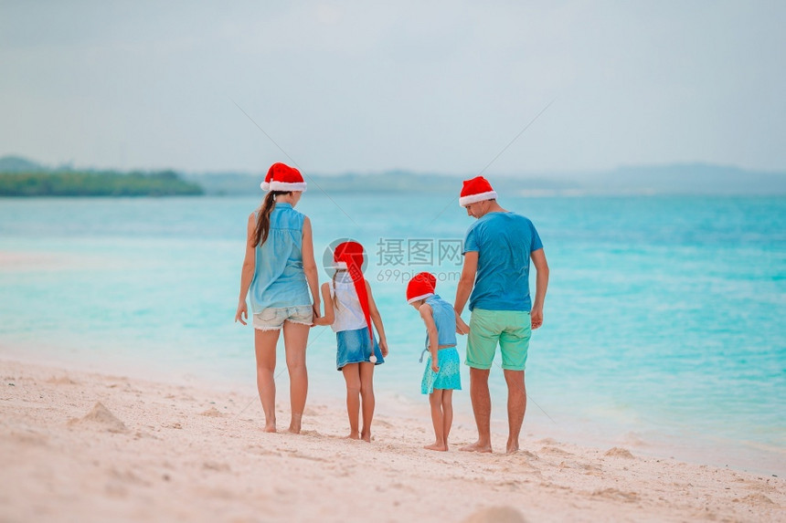 女孩欢乐家庭与两个孩子一起快乐家庭在暑假圣诞节日在塔帽和两个孩子在一起欢喜家庭与红圣诞帽子在热带海滩庆祝圣诞节度假为人父母绿松石图片