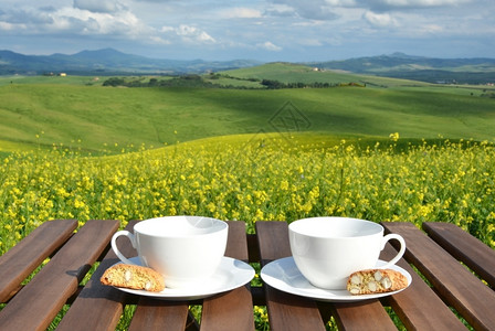 草地方格的木制桌上两个咖啡杯和罐子意大利托斯卡纳风景红色的图片