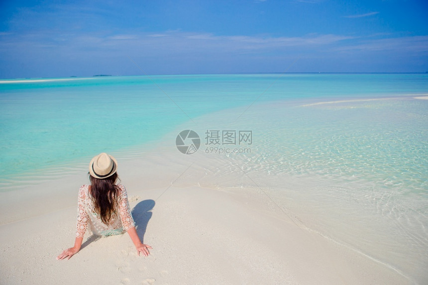 漂亮女孩背坐在沙滩上图片