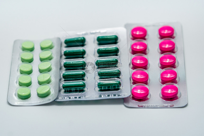 维他命健康白色背景上泡罩包装中的粉红色片剂和绿胶囊片剂止痛药制业房店背景产品全球医疗保健药片图片