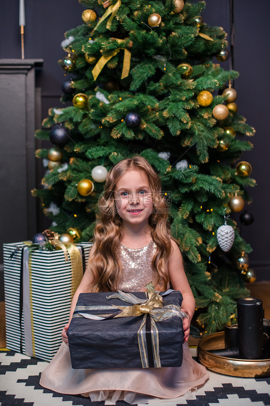 圣诞树下手拿礼物的小女孩图片