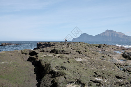 法罗群岛地貌的横向景象美丽的山峰和北大西洋以及无法辨识的年轻徒步者站立并拍摄附近GjogvGlografle村法罗群岛海报图案的图片