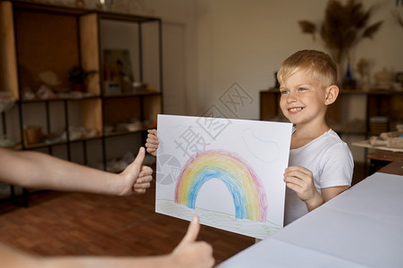 铅笔画小男孩展示他的绘画小男孩在艺术学校年轻画家愉快的爱好乐童年发展创意造的小男孩展示他绘画孩子在讲习班上展示调色板背景图片